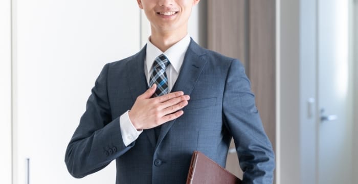 スーツを着て笑顔で胸に手を当てている男性が写る、不動産会社の紹介画像